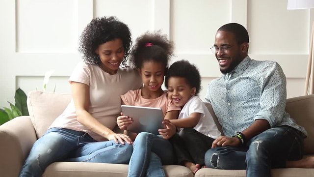 Cute african children play game using digital tablet with parents