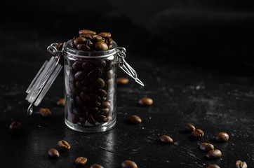 Glass jar with coffee beans on dark background. Close up of coffee. Copy space