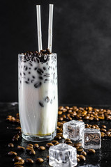 Iced coffee frappe with milk concept in a tall glass with the straws. coffee beans on a dark...