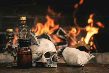 Alchemist or wizard or witch doctor table with magic accessories above on a burning fire background.