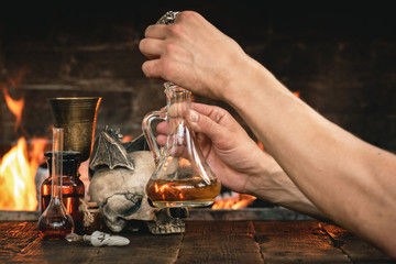 Alchemist or witch doctor or wizard is working at his magic table and producing a magic potion.
