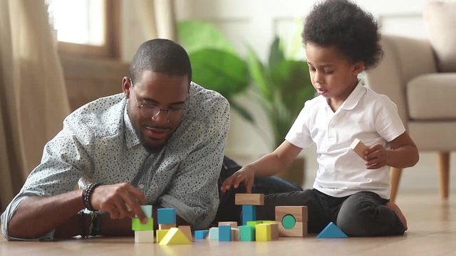 Loving single black father helping little kid son playing together