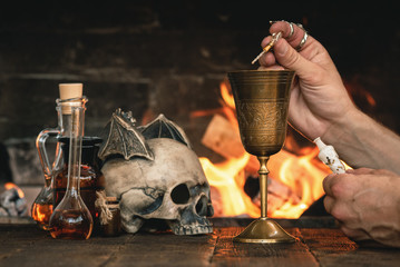 Alchemist or witch doctor or wizard is working at his magic table and producing a magic potion.