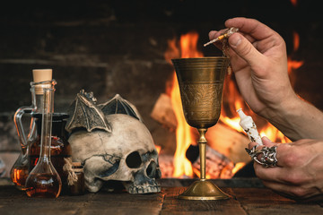 Alchemist or witch doctor or wizard is working at his magic table and producing a magic potion.