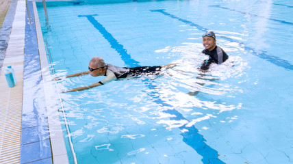 Elderly man learning swims with his son