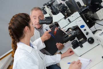 Teacher talking to student sat at microscope