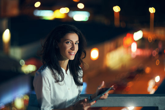 Woman Over Night Cityscape Holding A Digital Tablet Texting