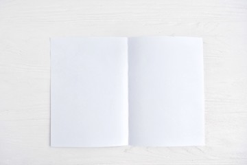 Blank sheet of white paper for design banner or card on textured neutral background, selective focus. Clear page with empty space for image or text on wooden white backdrop. Mockup concept 