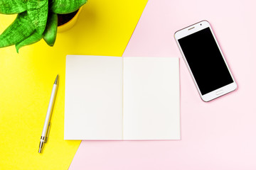 Notepad and a smartphone on the art yellow and pink background. Flat-lay, top view. Copy space for your text.