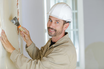 craftsman removes wallpaper with spatula