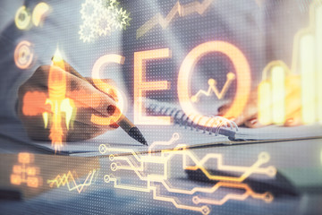 Double exposure of woman's hands making notes with SEO icon. Concept of Search engine optimization