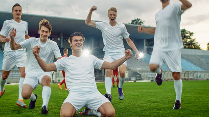 Captain of the Soccer Team Stands on His Knees Celebrates Awesome Victory, Makes YES Gesture Champion Team Joins Him. Successful Happy Football Players Celebrate Victory.