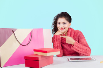 Smiling woman pointing shopping bags on studio