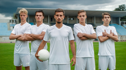 Professional Soccer Players Team Posing for a Group Photo Standing on a Football Field.