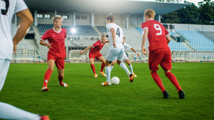 Shot of Professional Soccer Player Leads with a Ball, Masterfully Dribbling and Bypassing Sliding Tackles of His Opponents. Two Professional Teams are Playing Football Championship.