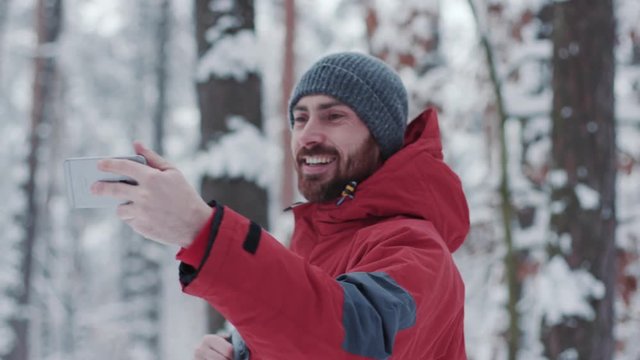 Close up happy young man traveler using smart phone in winter forest adventure cold jacket mobile nature phone tourist trip adult caucasian cell communication landscape slow motion