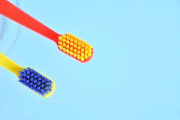 Two bright toothbrushes with soft focus on blurred blue background. Plastic toothbrush for personal daily oral hygiene. Dental healthcare. Tools for morning routine. Caries protection