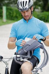 Naklejka premium cyclist sat on bicycle looking at a map for directions