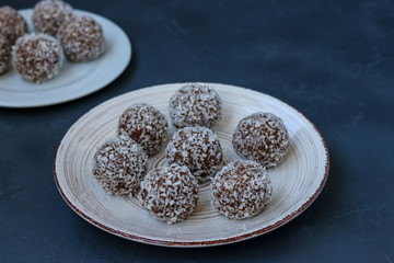 Curd balls with coconut shavings and chocolate chip cookies re located on a dark background, horizontal