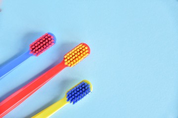 Three colorful plastic toothbrush with selective focus on blurred blue background. Multicolored...
