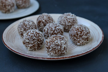 Curd balls with coconut shavings and chocolate chip cookies re located on a dark background, horizontal