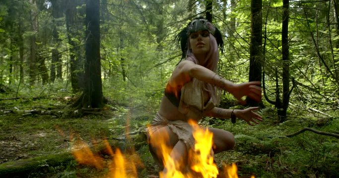 wild woman shaman invokes spirits in forest using sacred fire