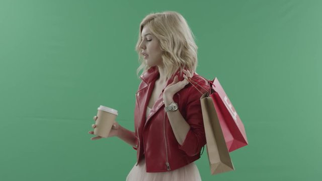 Charming woman drinks coffee afer shopping against green screen