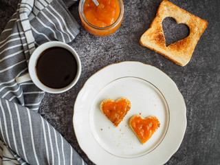 Toastbrot mit Aprikosenmarmelade in Herzform auf einem weißen Teller, Draufsicht, Frühstück, servierfertig