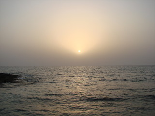 An unusual natural picture of the sunset on a colorful evening sky, which is reflected on the boundless sea surface tombled with ripples of small waves.