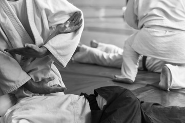 Black and white image of aikido. Hands of fighters. The traditional form of clothing in Aikido. Background image. No faces and recognizable elements
