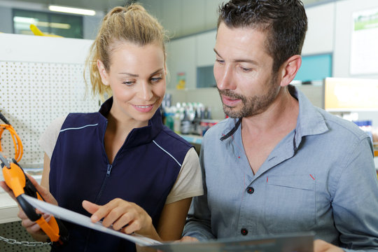 hardware store worker with customer looking at brochure