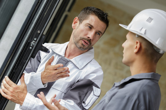 double-glazing installer in conversation with young apprentice