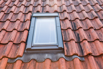 dirty orange roof tiles with small window.