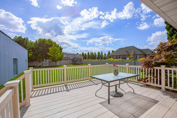 Balcony with view of the spacious yard under cloudy blue sky on a sunny day