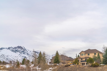 Homes with view of snow covered mountain and overcast sky in winter