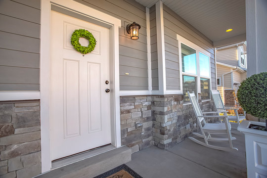 Facade Of A Home With A Simple Wreath Hanging On The White Wooden Door