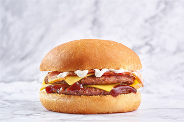 double cutlet burger with double cheese and bacon isolated at white marble background.