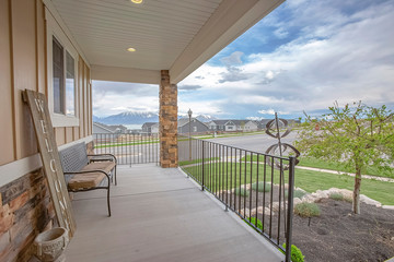 Porch overlooking yard road homes lake and mountain under cloudy blue sky