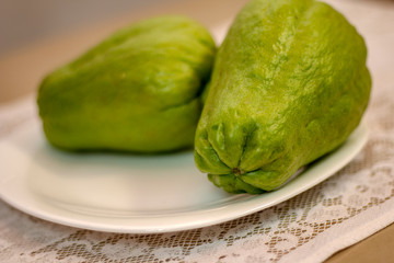 Two chuchus served on a white porcelain plate on a table covered with white lace tablecloth.