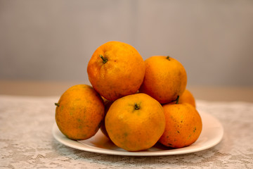 Tangerine served in white porcelain dish on a table covered with white lace towel.
