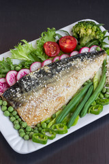 Grilled fish sprinkled with sesame with vegetables. Black background