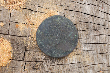 Fototapeta na wymiar Ancient copper coin of Tsarist Russia in 1757, the Romanov dynasty, against the background of wood.