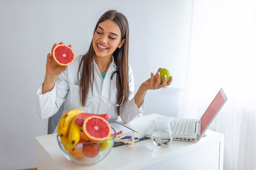 Doctor or nutritionist hold an apple. Good medical healthcare nutrition concept. An apple a day keeps the doctor away. Smiling Female nutritionist holding a green apple and showing healthy fruits