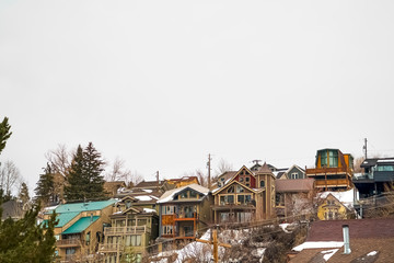 Fototapeta na wymiar Hill homes with balconies and snowy roofs against cloudy sky in winter
