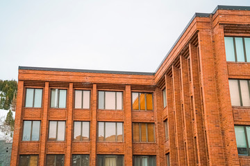 Exterior of red brick building with flat rooftop and shiny sliding windows