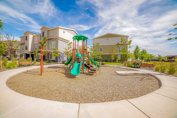 Playground surrounded by a circular pathway and benches under cloudy blue sky