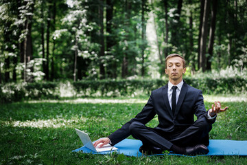 Man in a suit with tie. Business man relaxing in a park in the lotus position, he can't relax in...
