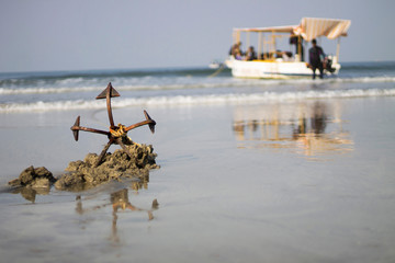 Anchor on a beach with boat in background, India.