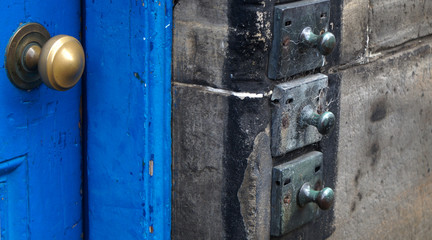 A doorway with a blue door and ancient door bells in a tenement building in Edinburgh, Scotland, UK