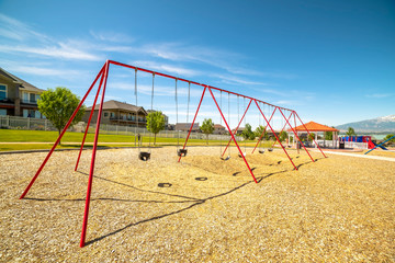 Fototapeta premium Park with swings pavilion and slides in front of homes and lake on a sunny day